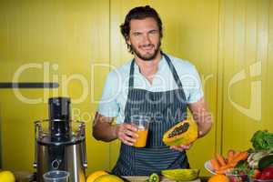 Portrait of smiling male staff holding glass of juice and papaya