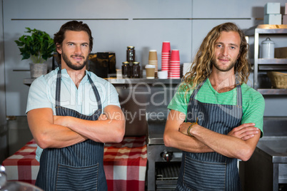 Portrait of smiling two male staff standing with arms crossed