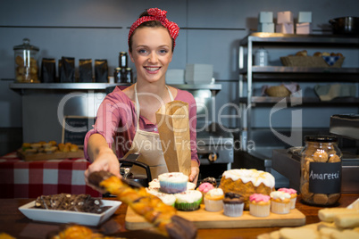 Female staff packing sweet food in paper bag