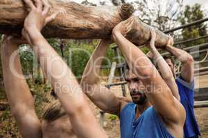 People lifting a heavy wooden log during boot camp