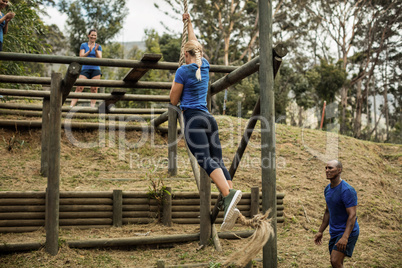 Fit woman climbing down the rope during obstacle course