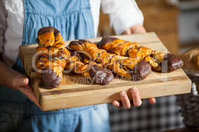 Mid-section of female staff holding sweet foods in bakery section