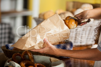 Staff packing bread in paper bag at bakery shop