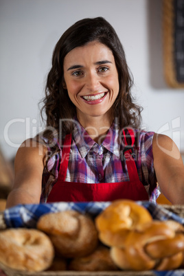 Portrait of female staff holding basket of sweet foods