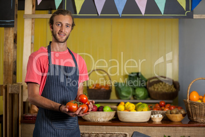 Portrait of male staff holding fresh tomatoes in organic section