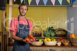 Portrait of male staff holding fresh tomatoes in organic section