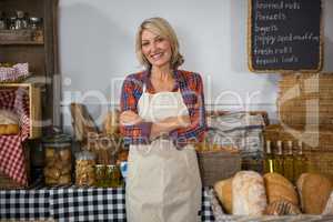 Portrait of smiling female staff standing with arms crossed at counter