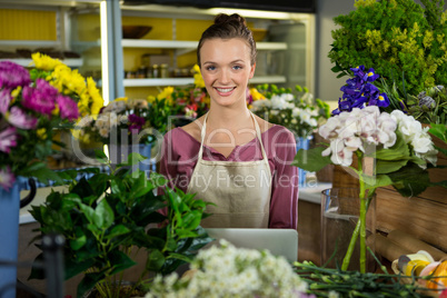 Happy female florist standing in flower shop