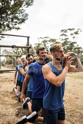People holding a heavy wooden log during boot camp