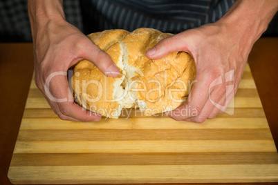 Male staff tearing a bun in bakery shop