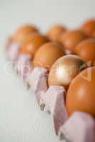 Easter eggs in carton on white surface