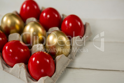 Close-up of red and golden Easter eggs in the carton