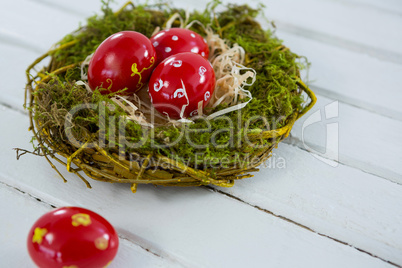 Red Easter eggs in the nest on wooden surface