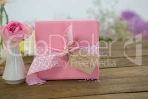 Gift box and flower vase on wooden surface