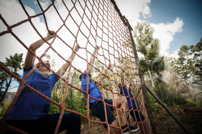 People climbing a net during obstacle course