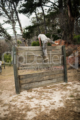 Soldier climbing wooden wall in boot camp