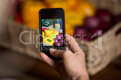 Hand of man taking photo of vegetables