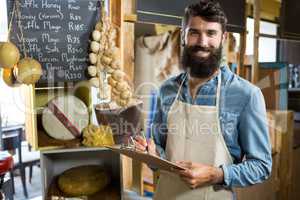 Salesman writing on clipboard at counter in grocery shop in market