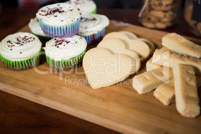 Cookies and cupcake on wooden board