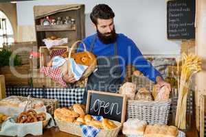 Male staff picking up bread from a wicker basket at counter