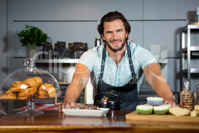 Portrait of smiling male staff standing near counter