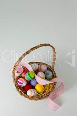 Various Easter eggs with ribbon in wicker basket