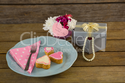 Open gift box with flower vase and heart shape cookies
