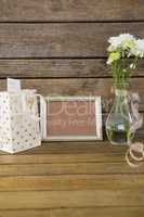 Gift bag, photo frame and flower vase on wooden surface