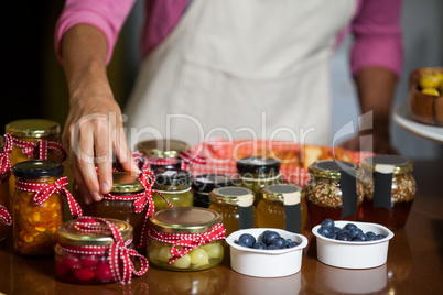 Mid-section of staff arranging jar at counter