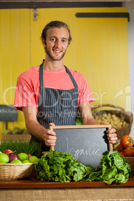 Portrait of male staff holding slate board in organic section