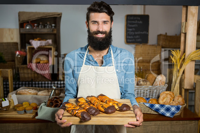 Portrait of male staff holding sweet food on board