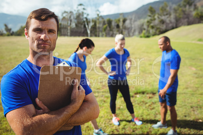 Fit man standing and holding a clipboard in boot camp