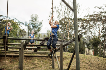 Fit woman climbing down the rope during obstacle course