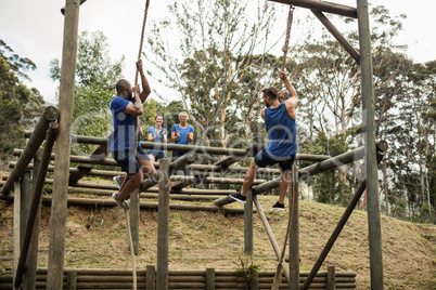 Fit men climbing down the rope during obstacle course