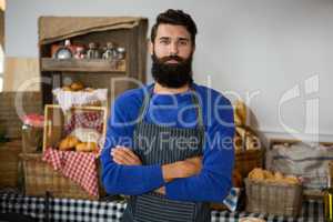 Portrait of male staff standing with arms crossed at counter