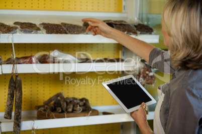 Female staff maintain records of meat on digital tablet at counter