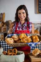 Female staff holding basket of sweet foods in bakery section