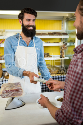 Customer paying bill by cash at meat counter