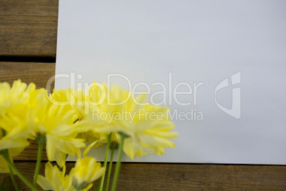 Yellow flowers with envelope on wooden plank