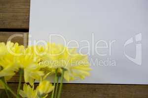 Yellow flowers with envelope on wooden plank