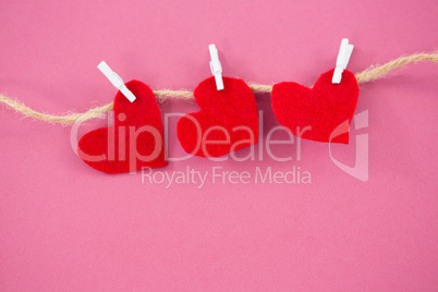 Red hearts with cloth peg hanging on rope