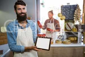 Portrait of smiling staff showing digital tablet at counter