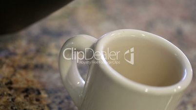 Pouring Coffee Into Coffee Mug on Granite Counter Top in Kitchen.