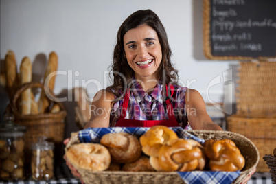 Portrait of female staff holding basket of sweet foods