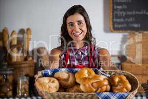 Portrait of female staff holding basket of sweet foods