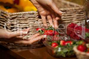 Hands of female staff holding bowl of strawberries