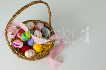 Various Easter eggs with ribbon in wicker basket