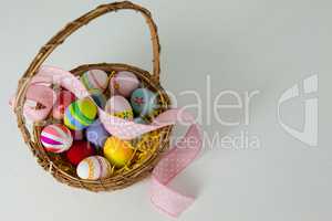 Various Easter eggs with ribbon in wicker basket