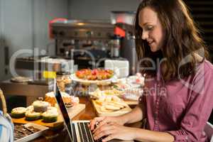 Woman using laptop at bakery counter