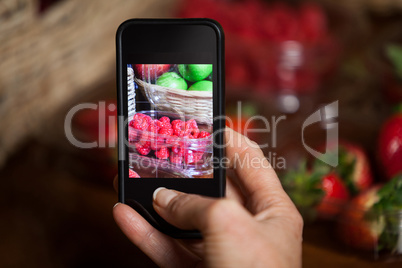 Hand of woman taking photo of fruits